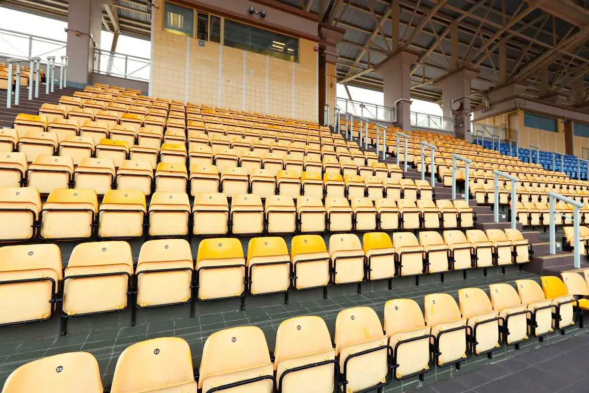 Puste żółte krzesełka na trybunach rcf arena czekają na kibiców.