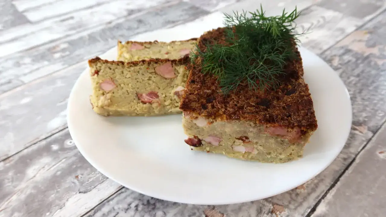 Babka ziemniaczana przepis babci: pyszne, domowe ciasto ziemniaczane z kawałkami boczku, udekorowane gałązką koperku.