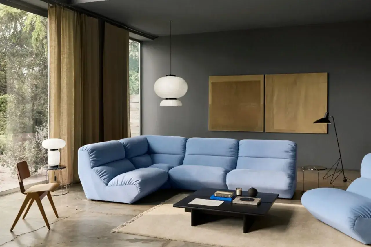 Modernes Wohnzimmer mit hellblauem Ecksofa, dunklem Couchtisch und Kunst an den W&auml;nden. Die dunkle Wandfarbe unterstreicht die aktuellen Wandfarben-Trends.