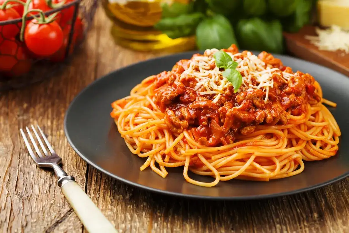 Pyszne spaghetti bolognese z wołowiny mielonej, posypane parmezanem i udekorowane bazylią. Idealne danie, gdy zastanawiasz się, jakie mięso mielone do spaghetti wybrać.
