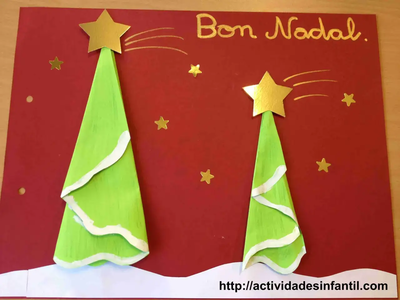Dos árboles de Navidad verdes con estrellas doradas y