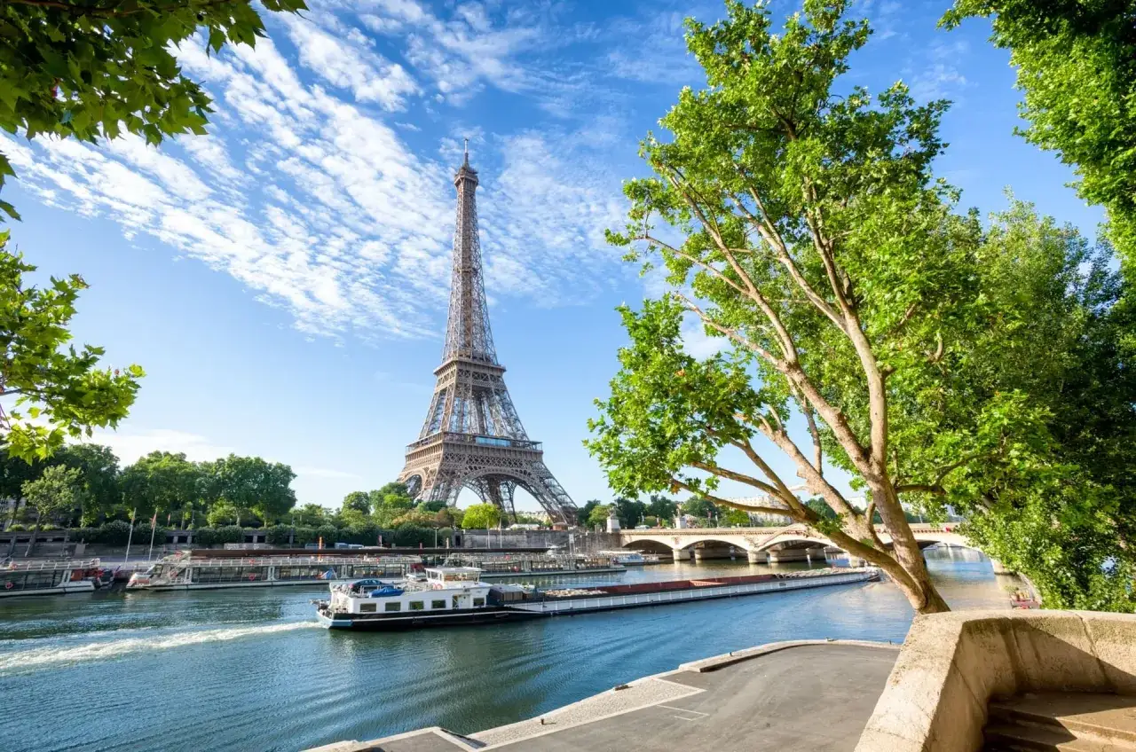 La Tour Eiffel se dresse fi&egrave;rement au-dessus de la Seine, un bateau navigue paisiblement. Id&eacute;al pour visiter Paris en 4 jours.
