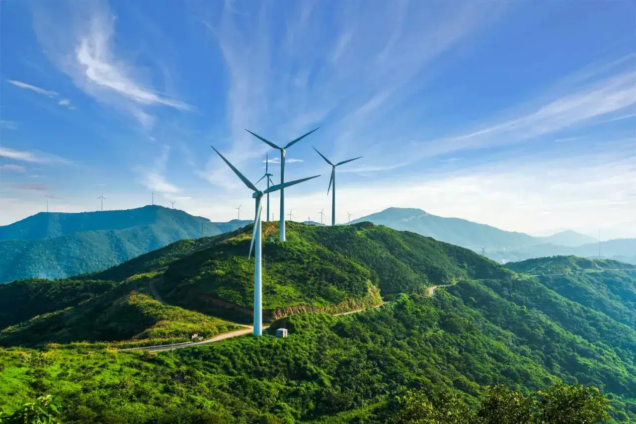 Wiatraki na zielonych wzg&oacute;rzach symbolizują zalety elektrowni wiatrowej: czystą energię i harmonię z naturą.