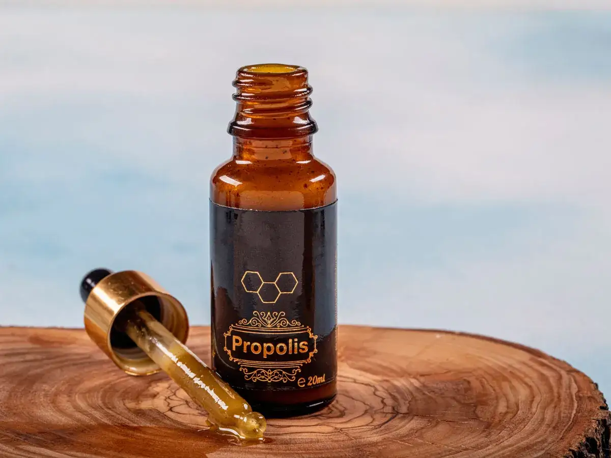 Propolis na zapalenie jelita grubego. Krople z propolisu w buteleczce z pipetką, na drewnianym tle.