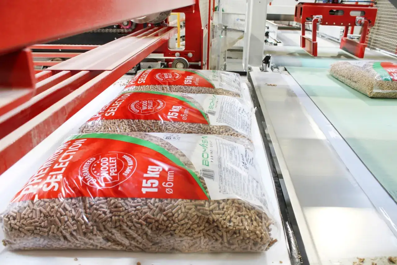 Workujące worki z pelletem drzewnym na taśmie produkcyjnej. To najlepszy pellet ranking, który zapewnia ciepło i ekologiczne ogrzewanie.