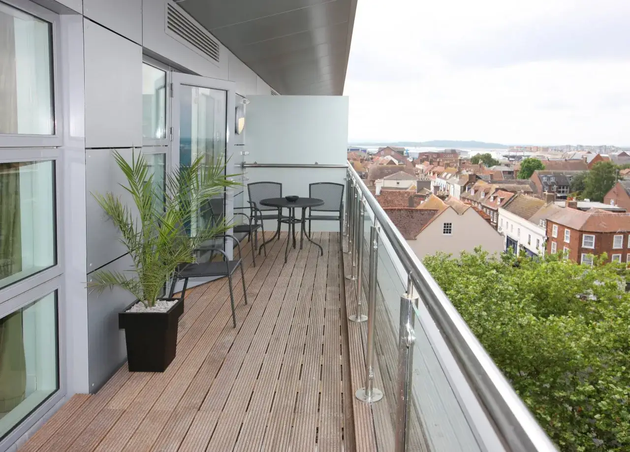 Une terrasse privative en copropriété avec vue sur les toits. Un palmier et un petit salon de jardin invitent à la détente.