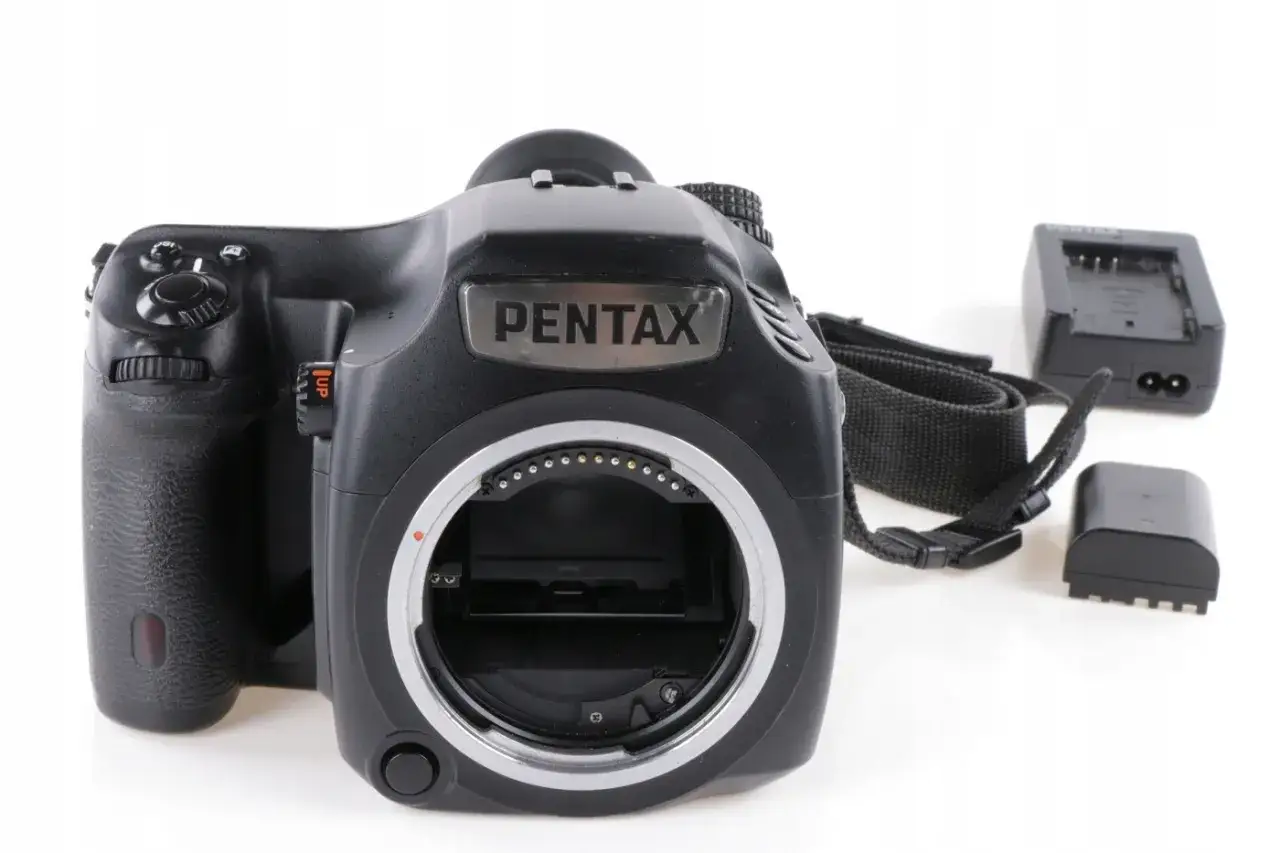 Czarna lustrzanka Pentax z paskiem, ładowarką i baterią. Idealna lustrzanka do 500 zł dla początkujących.