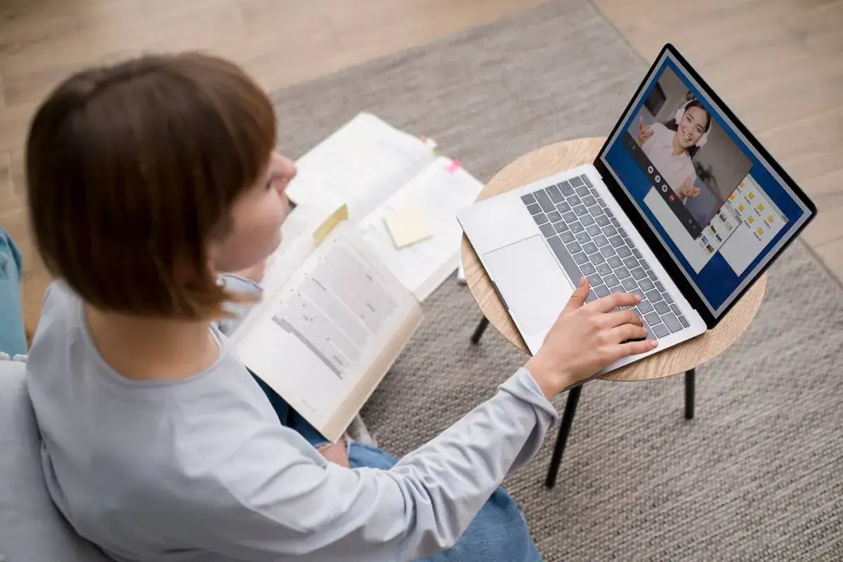 Étudiante en master de psychologie à distance, elle étudie sur son ordinateur portable et un livre ouvert.