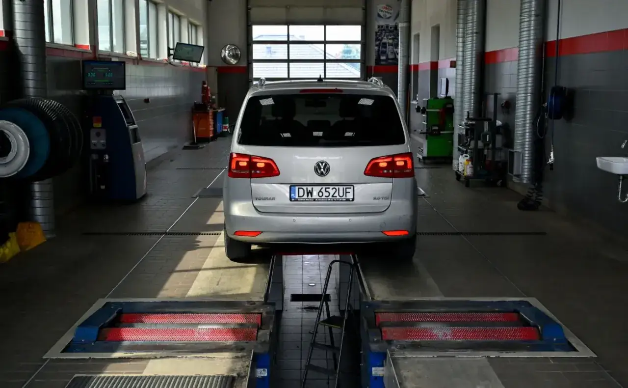 Srebrny Volkswagen Touran na podnośniku w warsztacie samochodowym. Zastanawiasz się, ile kosztuje przegląd samochodu?