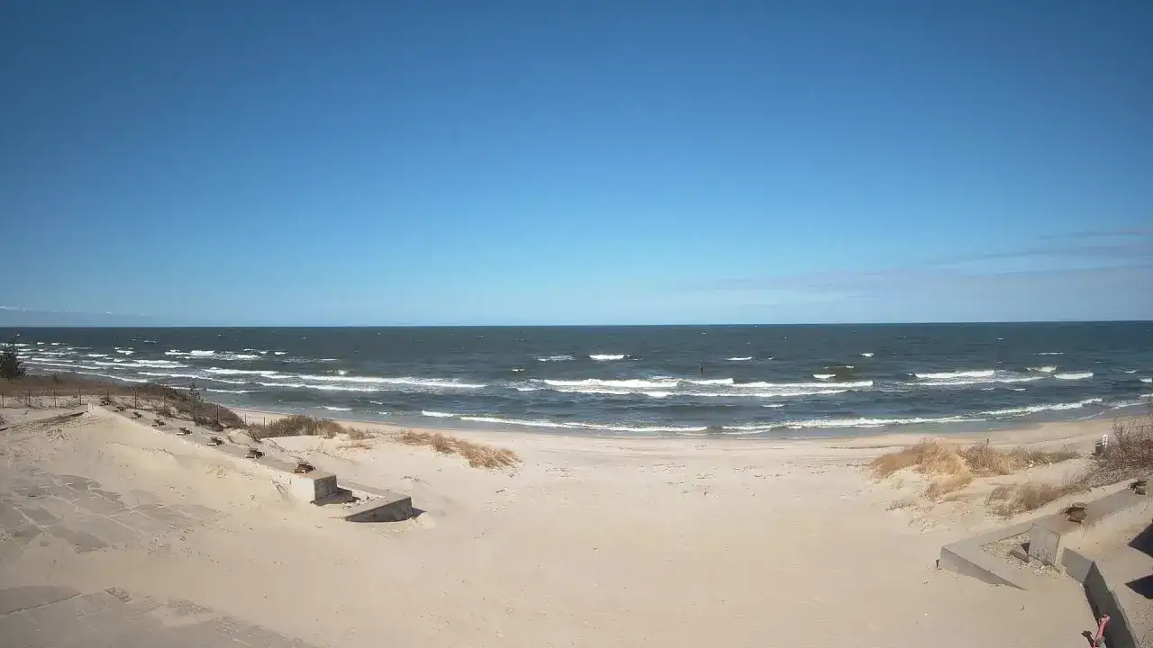 Plaża w Krynicy Morskiej, centrum miasta. Spokojne morze i piaszczyste wybrzeże pod błękitnym niebem.