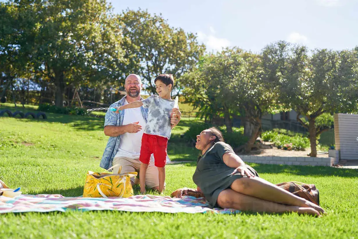 Familia divirtiéndose con burbujas en un picnic, un ejemplo perfecto de actividades para hacer en familia fuera de casa.