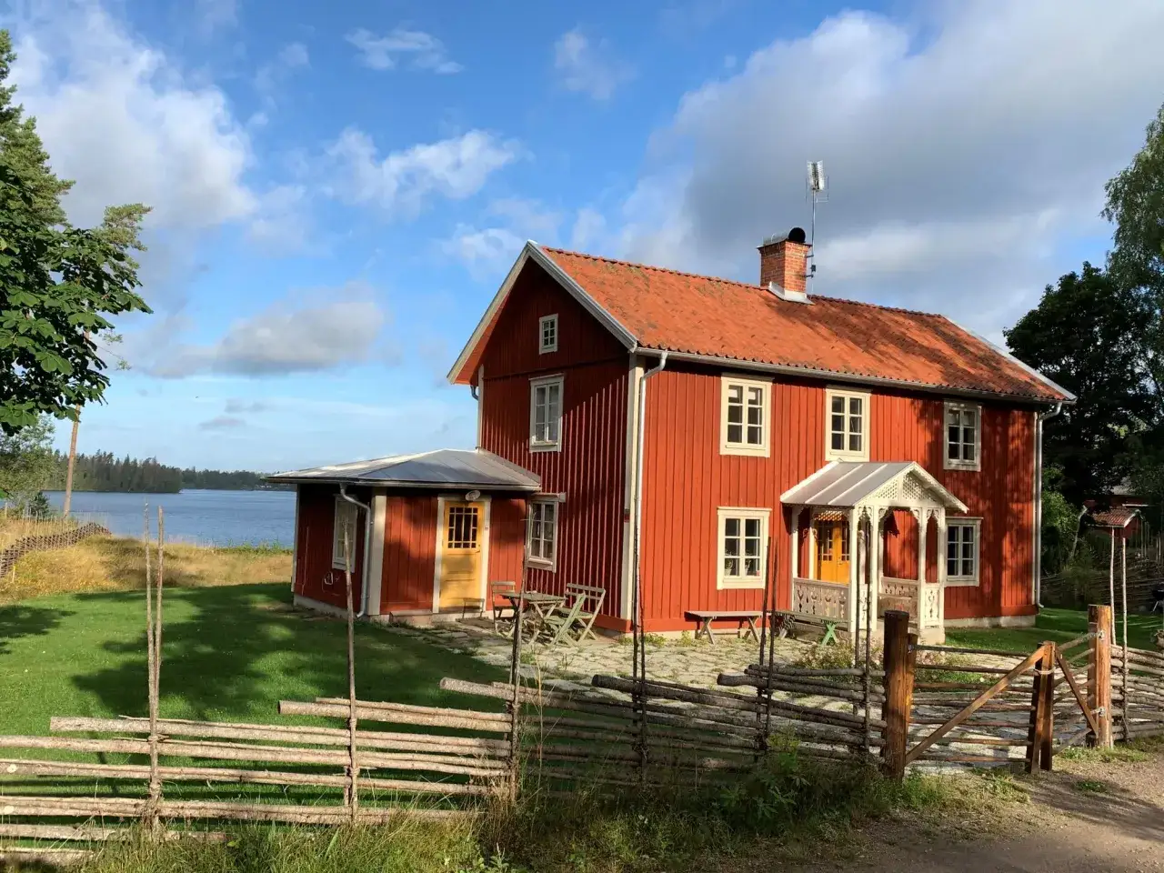 R&ouml;tt hus vid sj&ouml; i Tiveden. Ett idylliskt tiveden boende med en vacker tr&auml;dg&aring;rd och en rustik tr&auml;staket.
