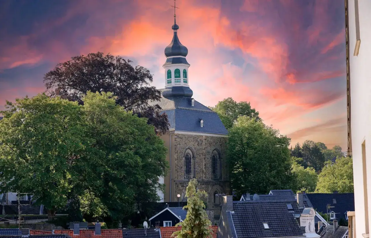 Kirchturm in Solingen Altstadt vor dramatischem Abendhimmel.