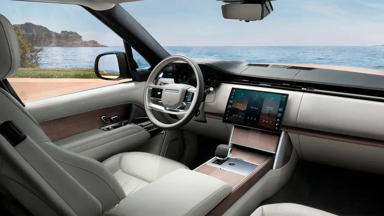 Wnętrze Range Rover Autobiography z widokiem na morze i wyspę. Luksusowe fotele, drewniane wykończenia i nowoczesny ekran.
