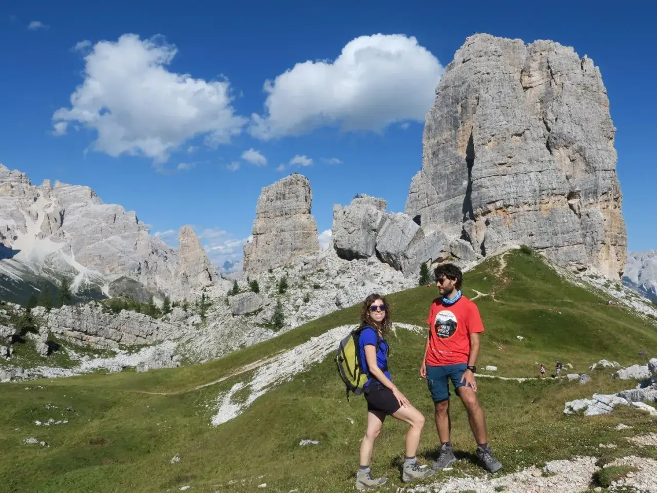 Pareja disfrutando de la ruta Cinque Torri, con imponentes formaciones rocosas y un cielo azul vibrante.