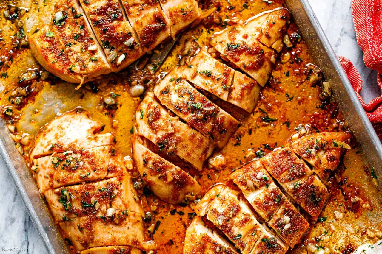 Soczysta pierś z kurczaka pieczona w aromatycznym sosie z czosnkiem i ziołami, pokrojona na kawałki.