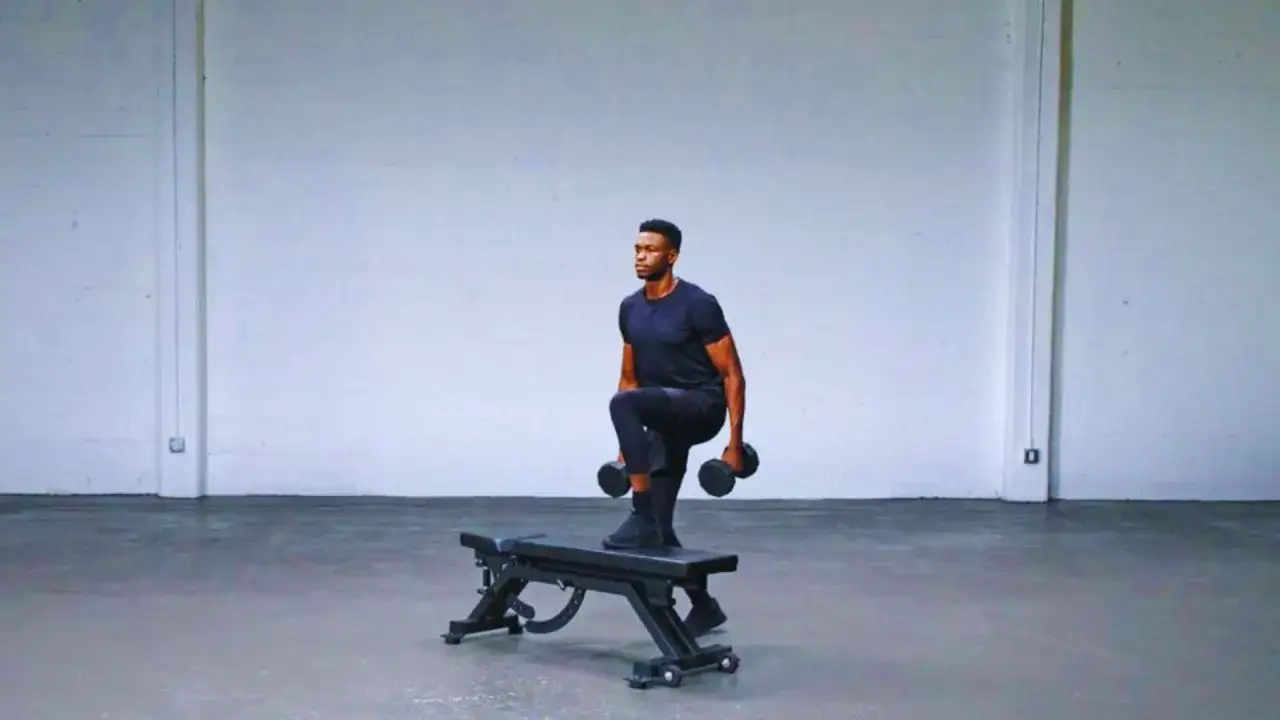 Uomo con manubri esegue step up exercise su panca, allenamento gambe e glutei.
