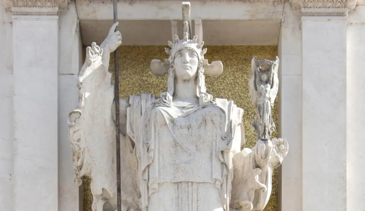 Statua imponente dell'Altare della Patria, con una figura femminile coronata che regge una lancia e una statuetta alata.