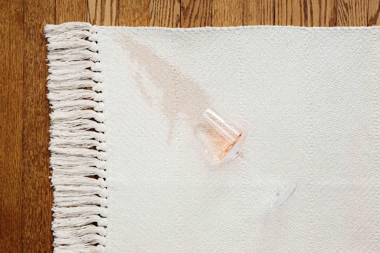 Un verre renvers&eacute; sur un tapis blanc laisse une tache ros&eacute;e. Est-ce que l'alcool &agrave; 70 tache les v&ecirc;tements ? La r&eacute;ponse est ici.
