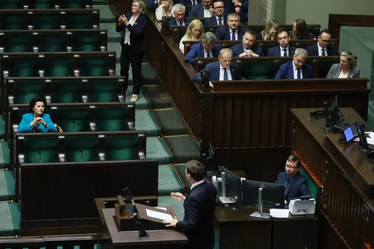 Posłanka opozycji filmuje obrady, podczas gdy inni politycy siedzą w ławach sejmowych.