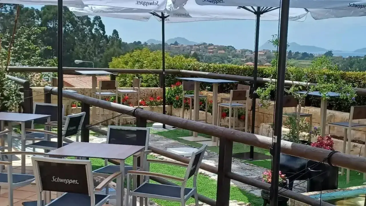 Terraza con mesas y sillas, ideal para disfrutar de restaurantes con encanto en Vigo y alrededores. Vista panorámica.
