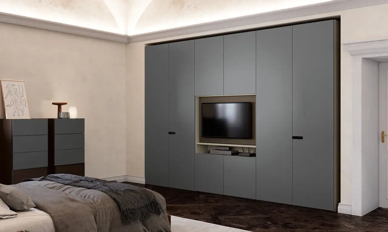 Armadio grigio con nicchia centrale per la **posizione TV camera da letto**. Sotto, mensole e vani contenitori.