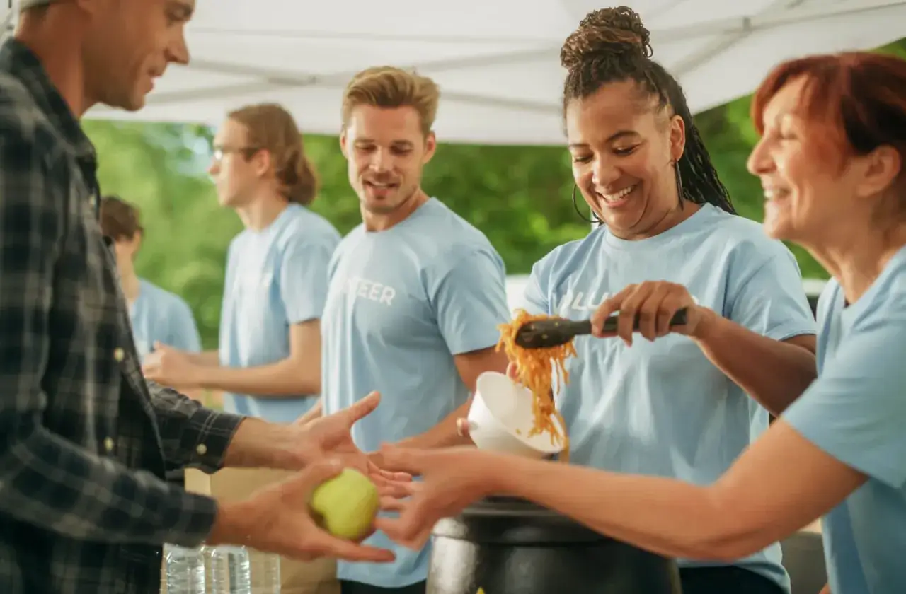 Volunteers serve food at a community event, showcasing what are some community services.