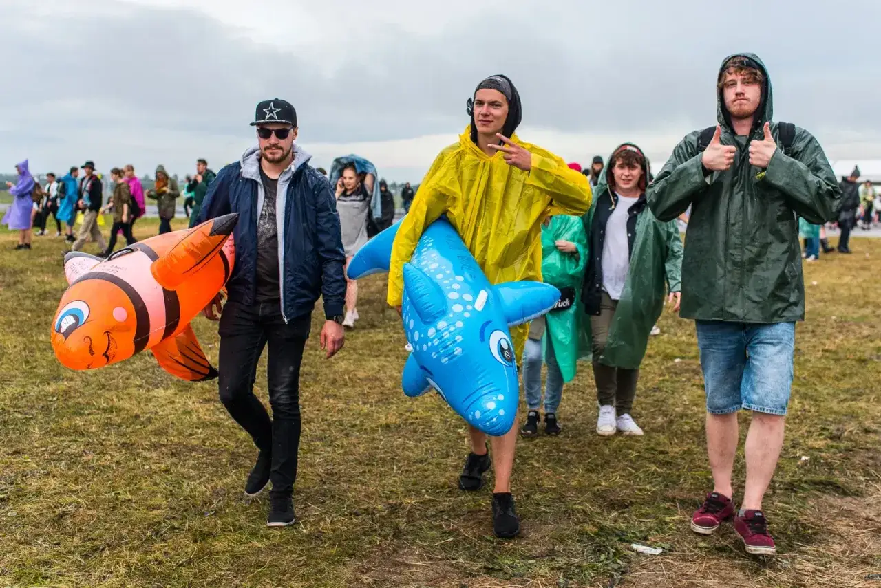 Ludzie w płaszczach przeciwdeszczowych idą z dmuchanymi rybkami. Co robić w Gdańsku jak pada? Festiwalowe atrakcje!