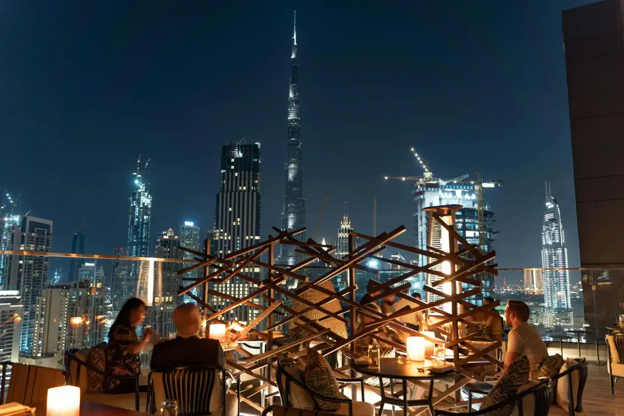Wieczorny widok na Dubaj z tarasu restauracji, w tle majestatyczny Burj Khalifa i inne drapacze chmur.