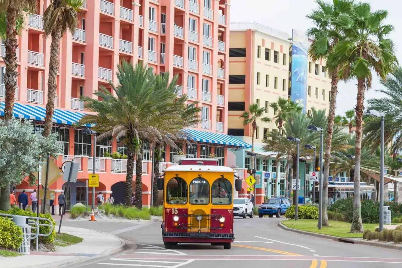 Bunte Geb&auml;ude und Palmen s&auml;umen die Stra&szlig;e, auf der ein gelber Trolleybus f&auml;hrt. Perfekt f&uuml;r die beste Reisezeit Florida!