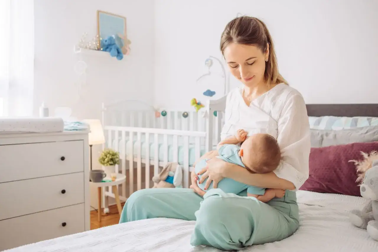 Eine Mutter stillt ihr Baby im Schlafzimmer. Ashwagandha kann in der Stillzeit helfen, Stress abzubauen.