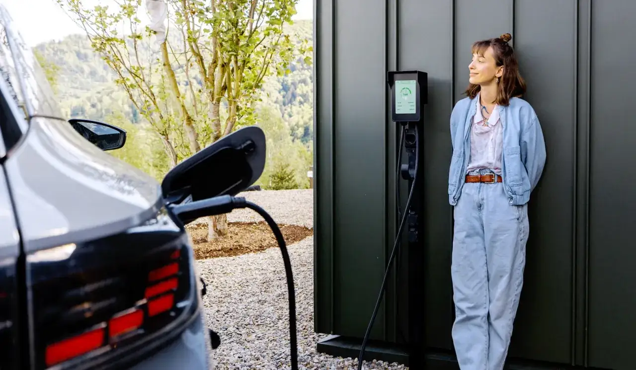 Kobieta czeka na naładowanie samochodu elektrycznego. Zastanawia się, ile kosztuje samochód elektryczny, gdy widzi dane ładowania.