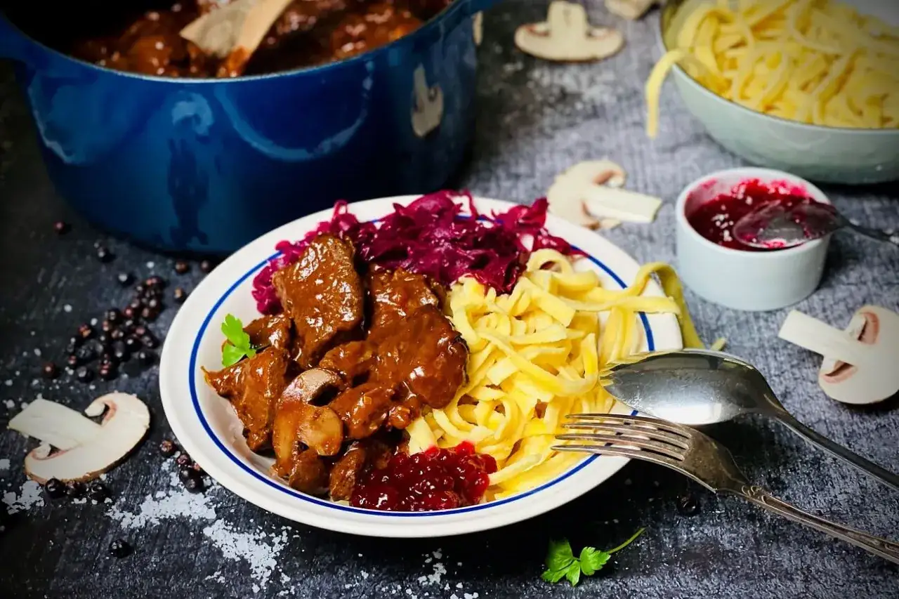 Herzhaftes Rehgulasch mit Rotwein, serviert mit Sp&auml;tzle, Rotkohl und Preiselbeeren. Ein k&ouml;stliches Gericht, das zum Nachkochen einl&auml;dt.