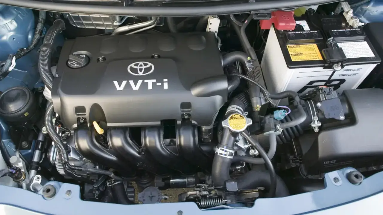 Silnik VVT-i z Toyoty Yaris 2. Widoczny akumulator, przewody i elementy układu dolotowego.