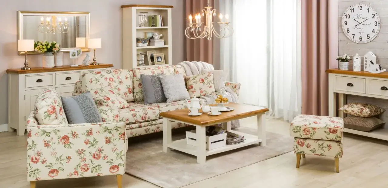 Przytulny salon w stylu shabby chic z kwiecistą sofą, stolikiem kawowym i kominkiem.
