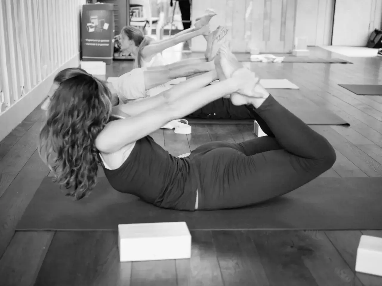 Clase de jivamukti yoga que es: practicantes en postura de arco, estirando espalda y piernas.