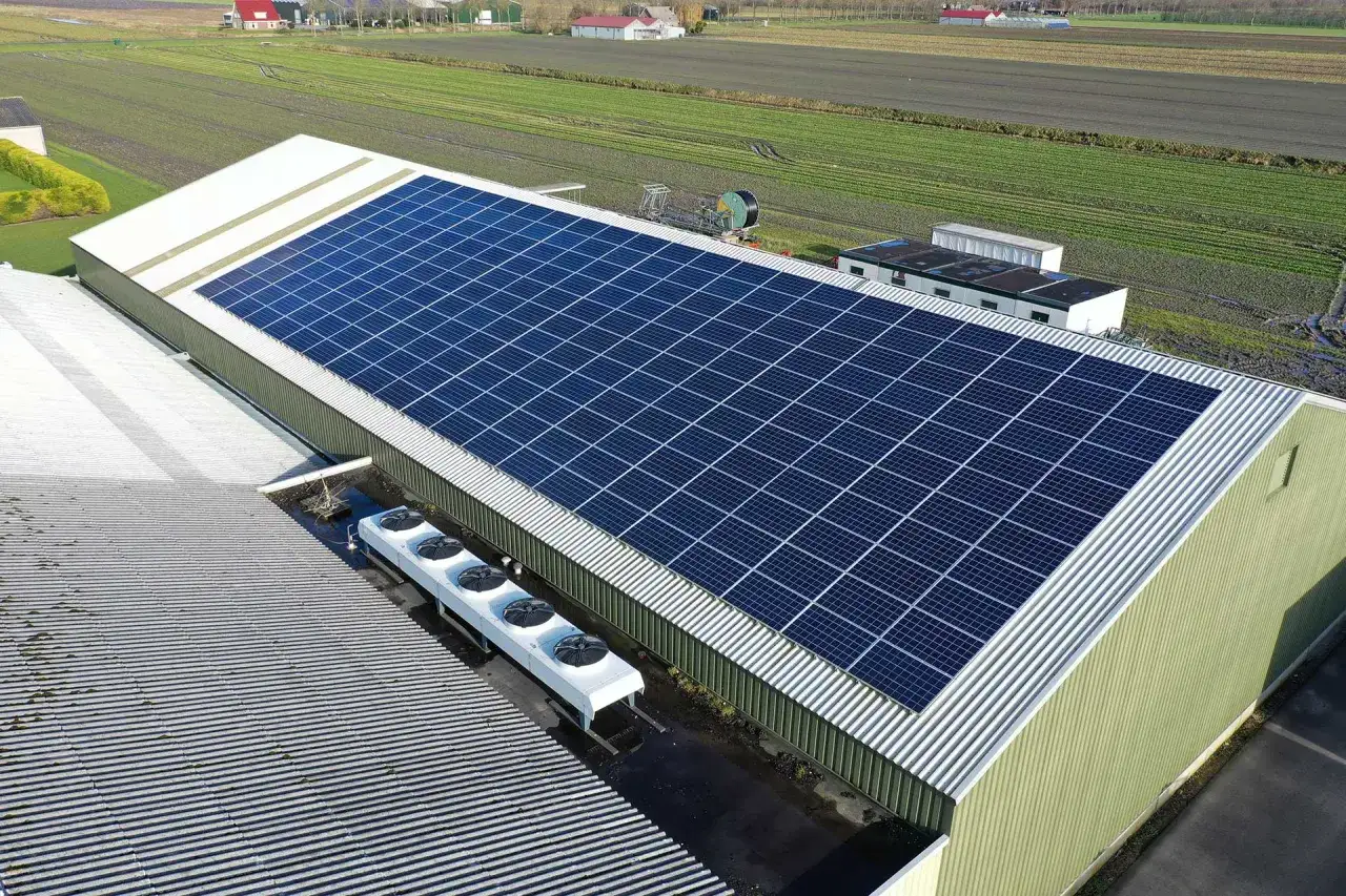 Duży magazyn energii 100 kWh z panelami słonecznymi na dachu. Obok instalacja chłodnicza.