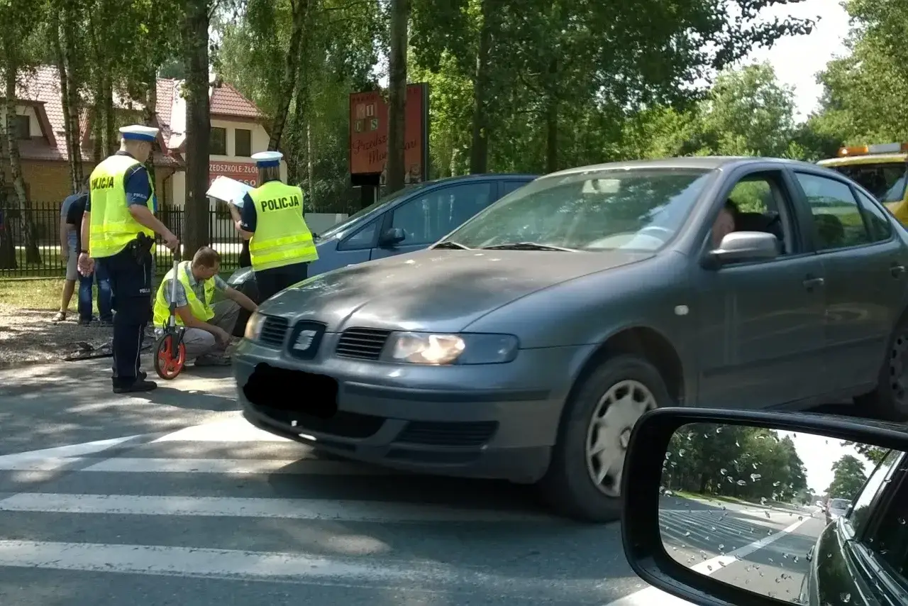 Policjanci badają miejsce kolizji. Jeden z nich mierzy odległość, drugi spisuje notatki. Kierowca szarego auta, który próbował ucieczka z miejsca kolizji, został zatrzymany.