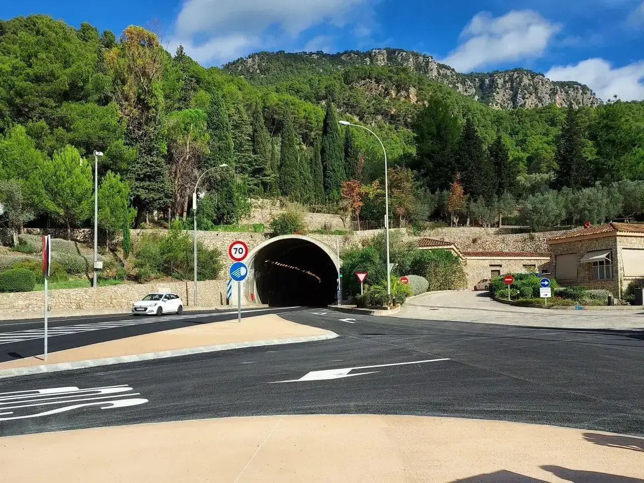 Tunnel-Einfahrt auf Mallorca, umgeben von gr&uuml;nen H&uuml;geln. Die 