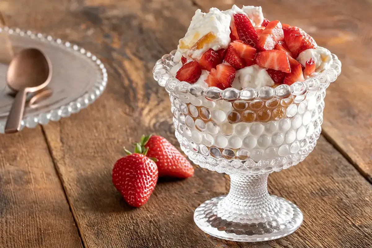 Delizioso tiramisù fragole in coppa di vetro, con fragole fresche e panna montata.
