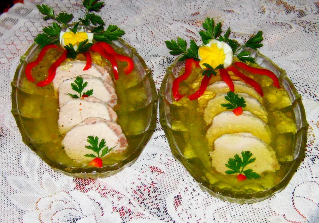 Dwa talerze z soczystym schabem w galarecie, ozdobione jajkiem, papryką i natką pietruszki. Idealne na święta!