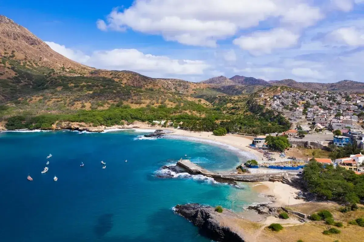 Idealne miejsce, gdzie na wakacje w sierpniu: błękitna zatoka, piaszczysta plaża, góry i miasteczko na wzgórzu.