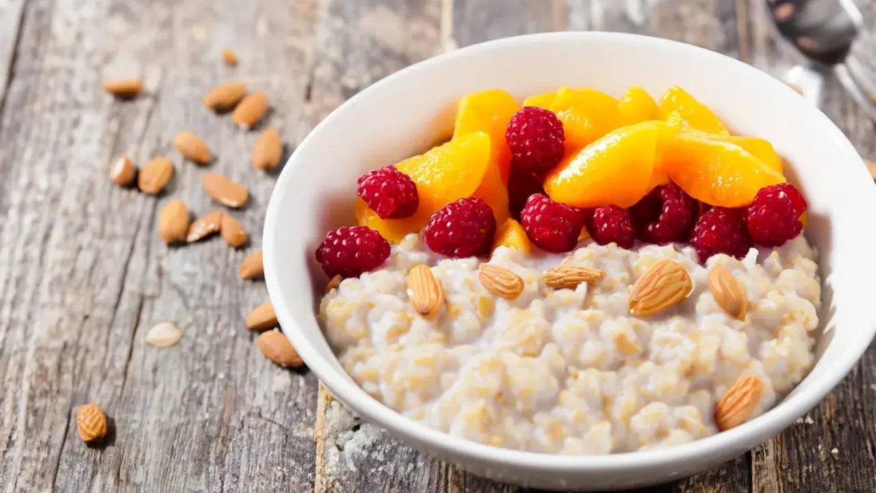 Un taz&oacute;n de porridge cremoso con frambuesas, melocot&oacute;n y almendras. Una gu&iacute;a visual de como hacer porridge saludable y delicioso.