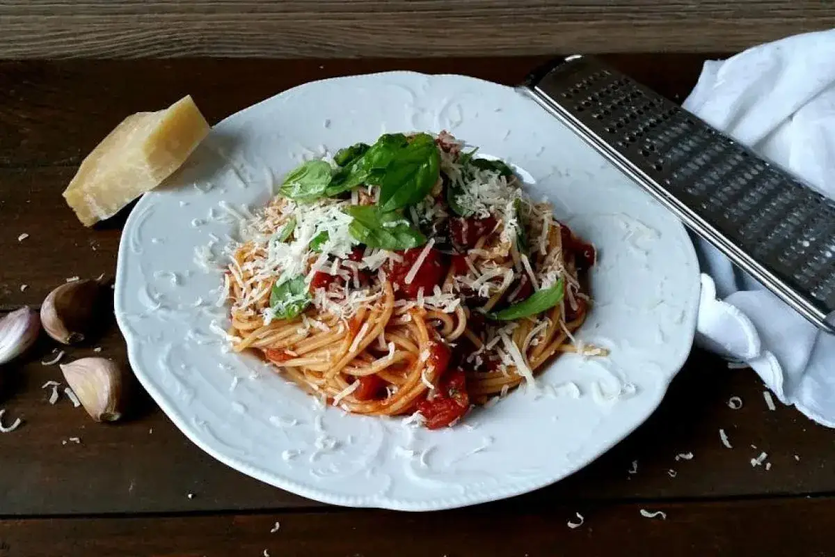 Pyszne spaghetti z pomidorami i bazylią, posypane parmezanem. Idealne, by dowiedzieć się, jak zrobić spaghetti.