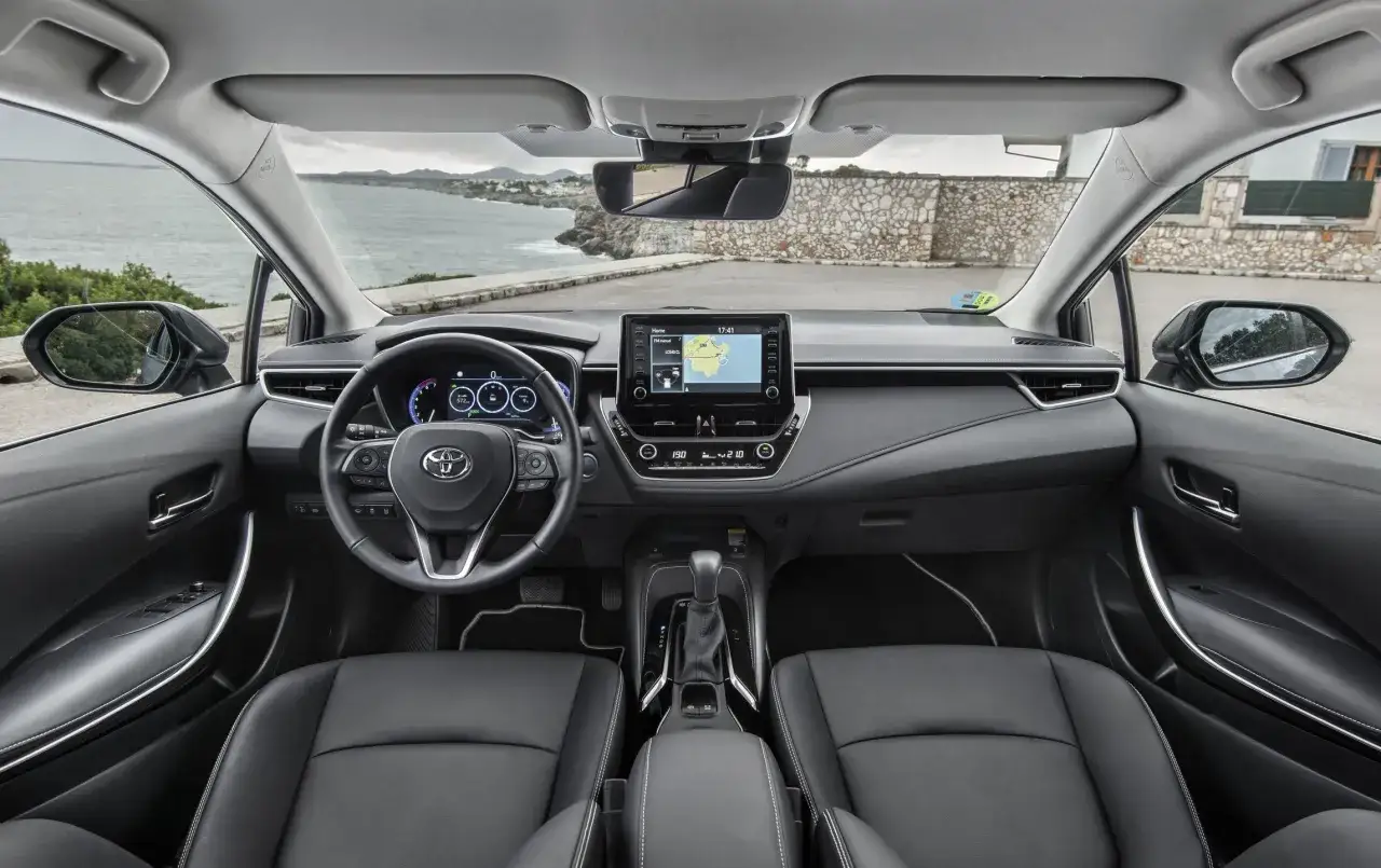 Wnętrze Toyoty Corolli 2017 z czarną skórzaną tapicerką, ekranem nawigacji i widokiem na morze.