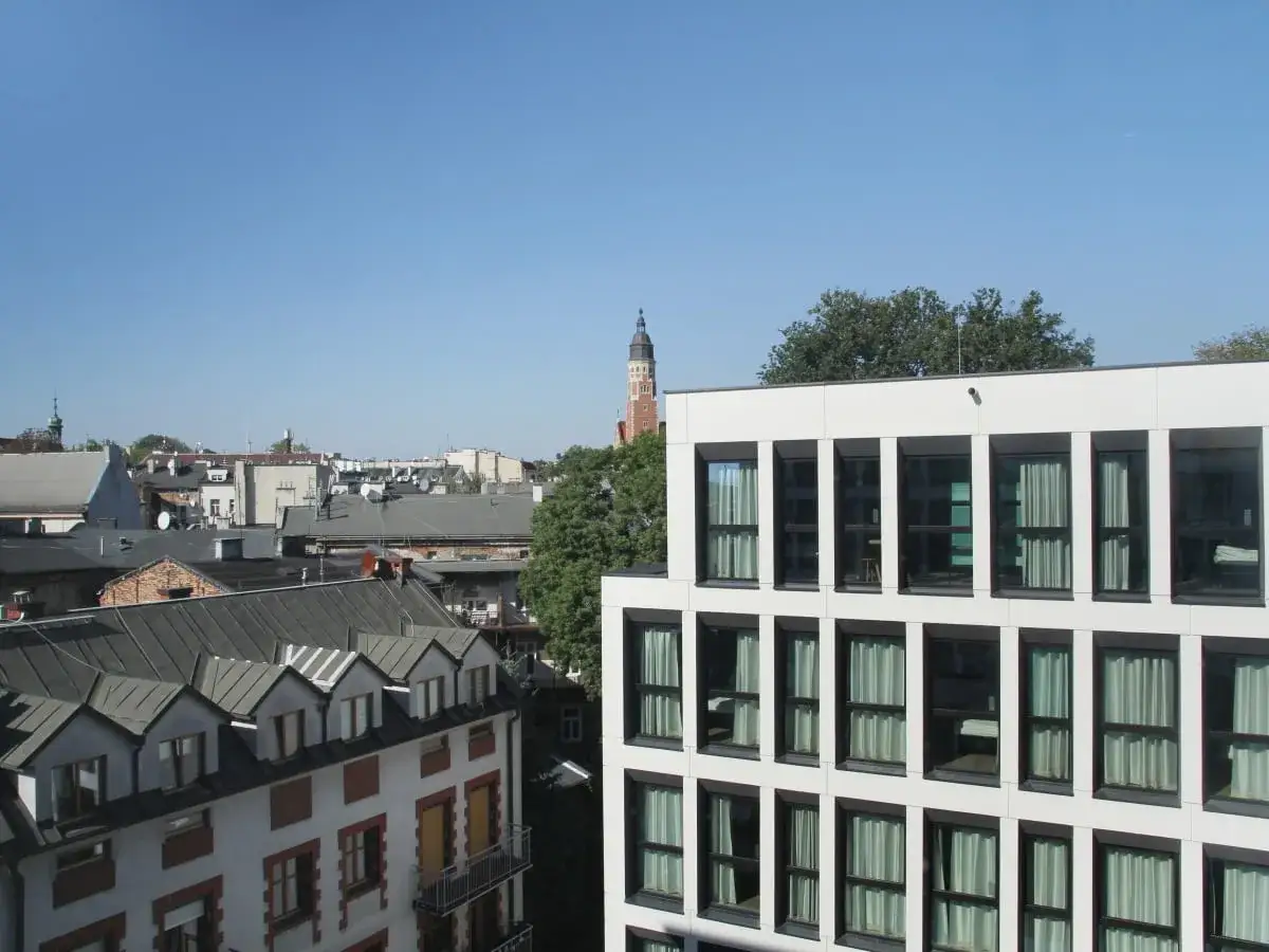 Widok na krakowską panoramę z nowoczesnym budynkiem Meininger Hotel Kraków i zabytkowymi kamienicami w tle.