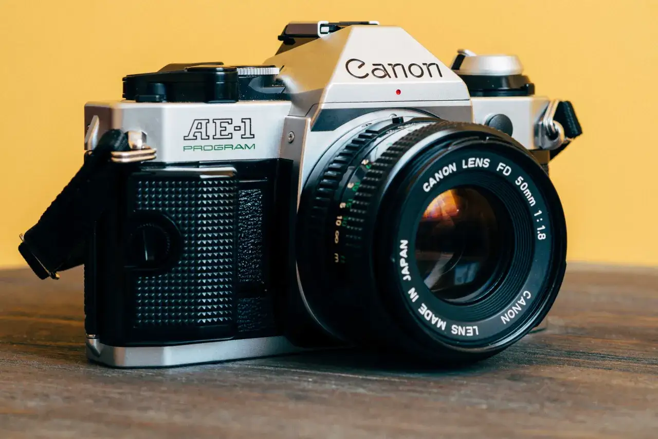 A silver Canon AE-1 Program camera with a 50mm 1:1.8 lens, ready for its best film.
