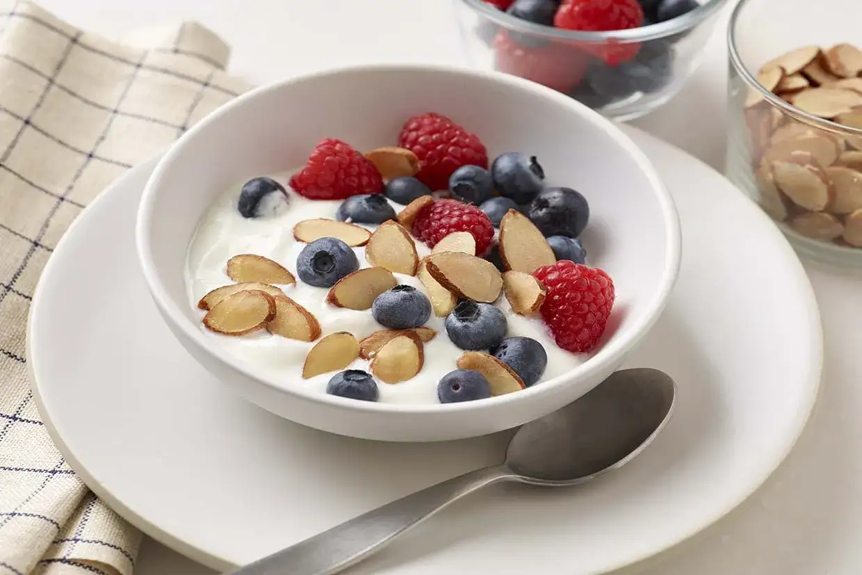 Yogur cremoso con ar&aacute;ndanos, frambuesas y almendras laminadas, un desayuno o postre saludable perfecto.