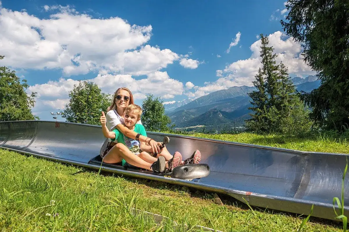 Mama z synkiem na kolejce grawitacyjnej w Zakopanem, z widokiem na Tatry. Uśmiechnięci i gotowi na zjazd!
