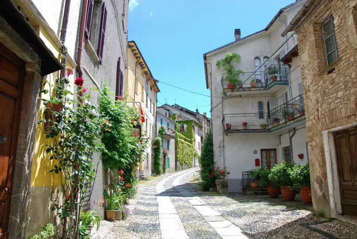 Un vicolo fiorito a Compiano, con case antiche e balconi adornati di piante. Un luogo incantevole da esplorare, con tante cose da vedere.